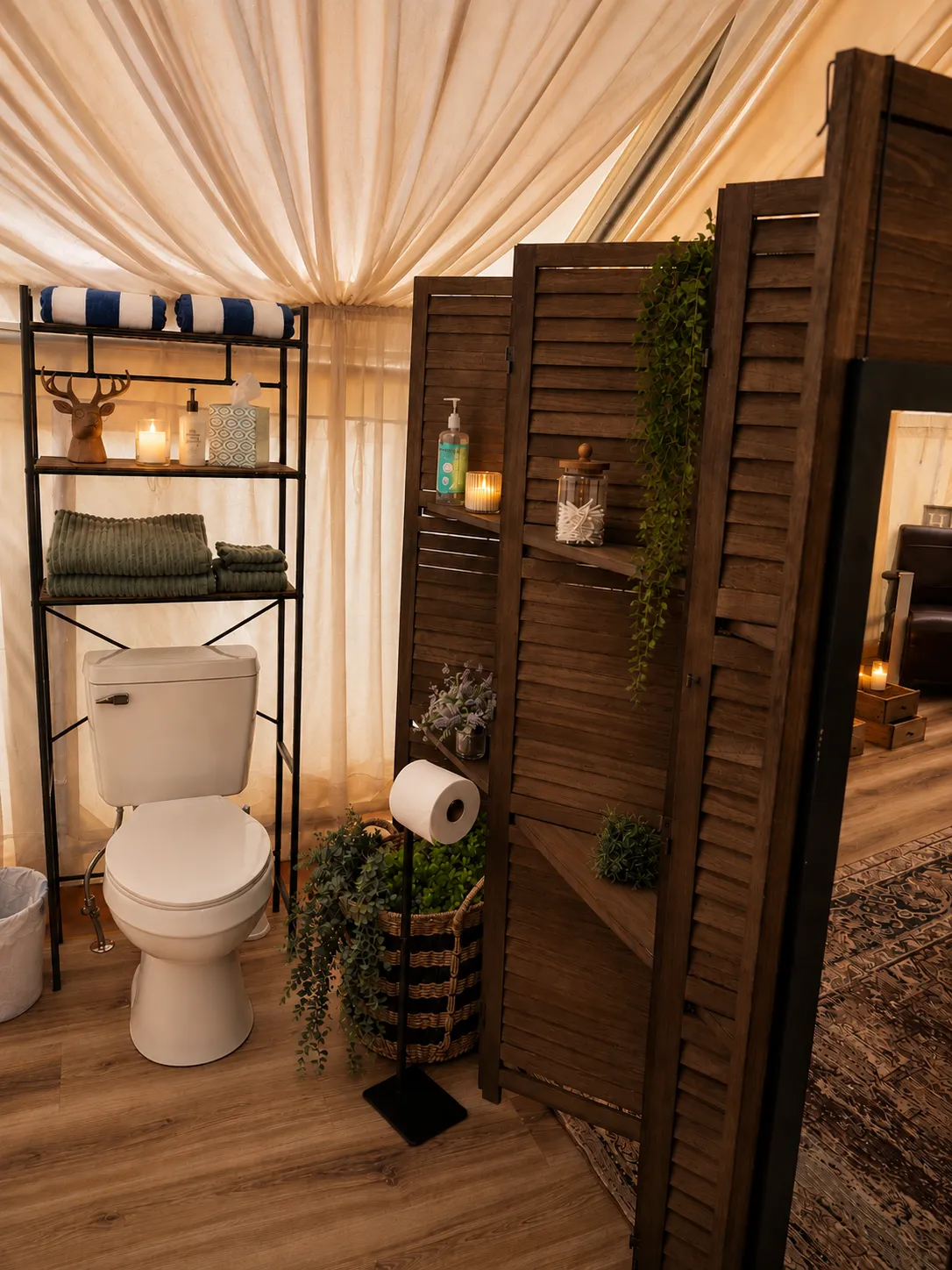 The Velvet Buck's private toilet inside the tent, screened by a louvered wooden divider, with folded towels, a candle and toiletries on the shelving beside it.